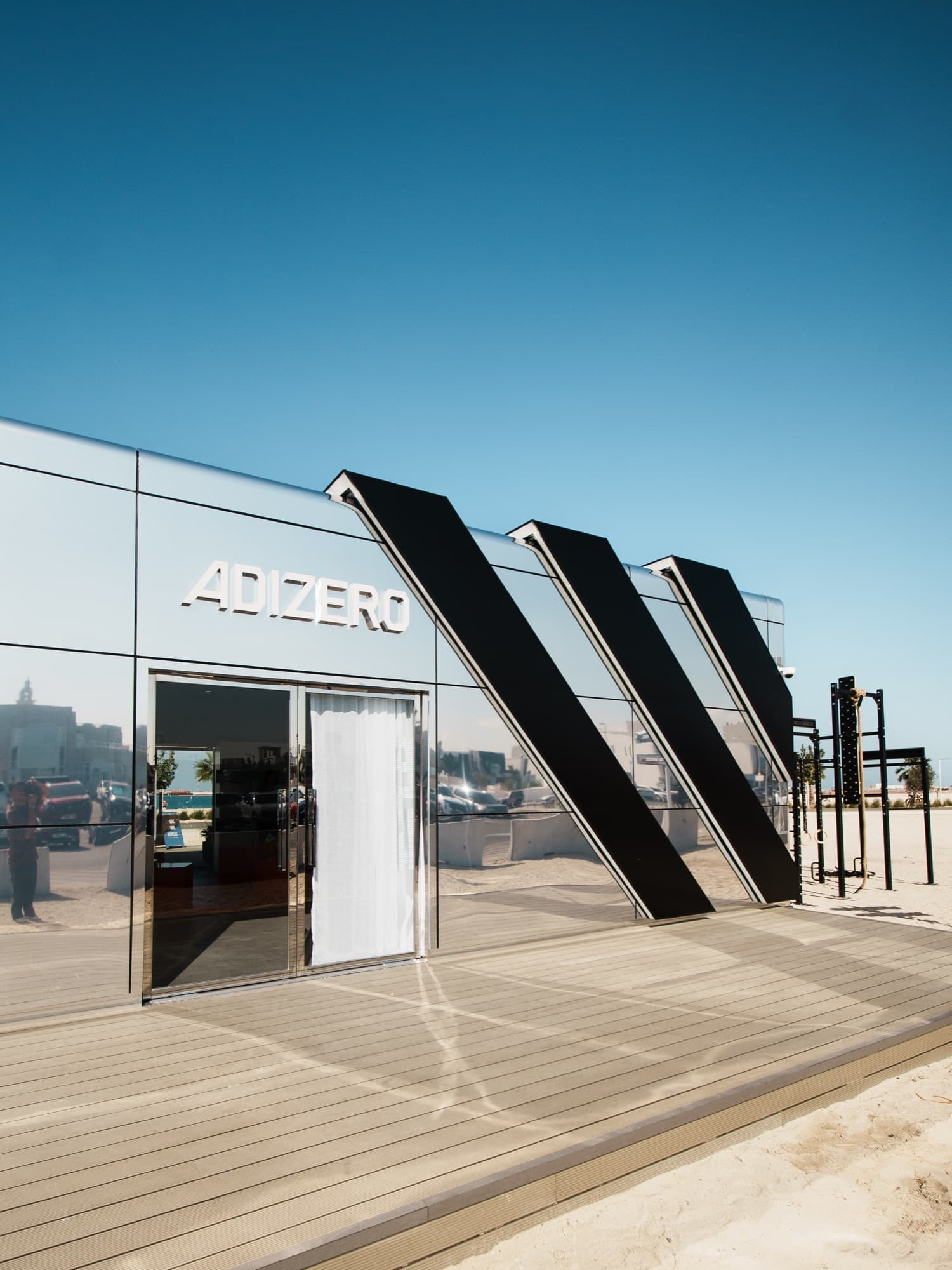 The mirrored Adizero pavilion with its three giant stripes on the beach at Umm Suqeim